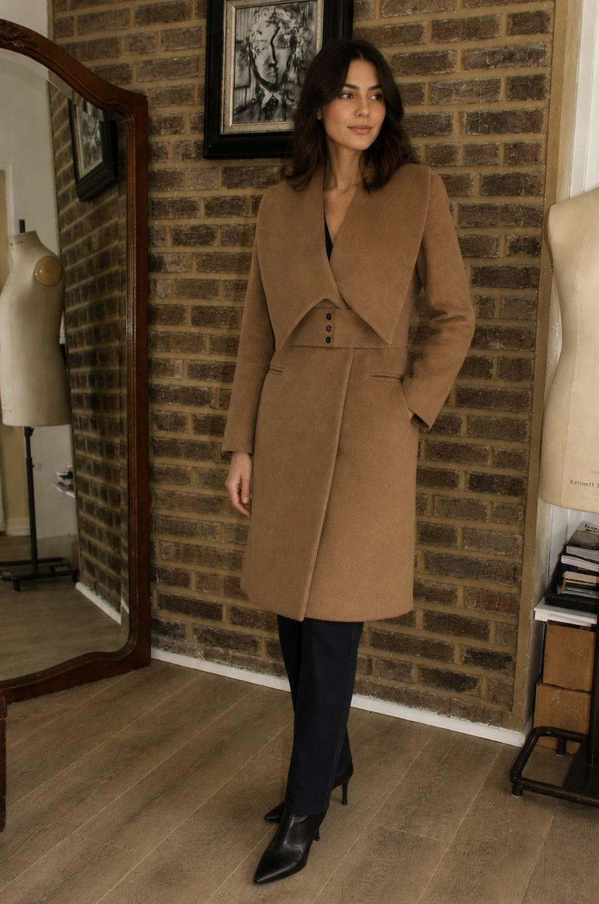 A camel wool coat with a sculpted collar, worn in the studio