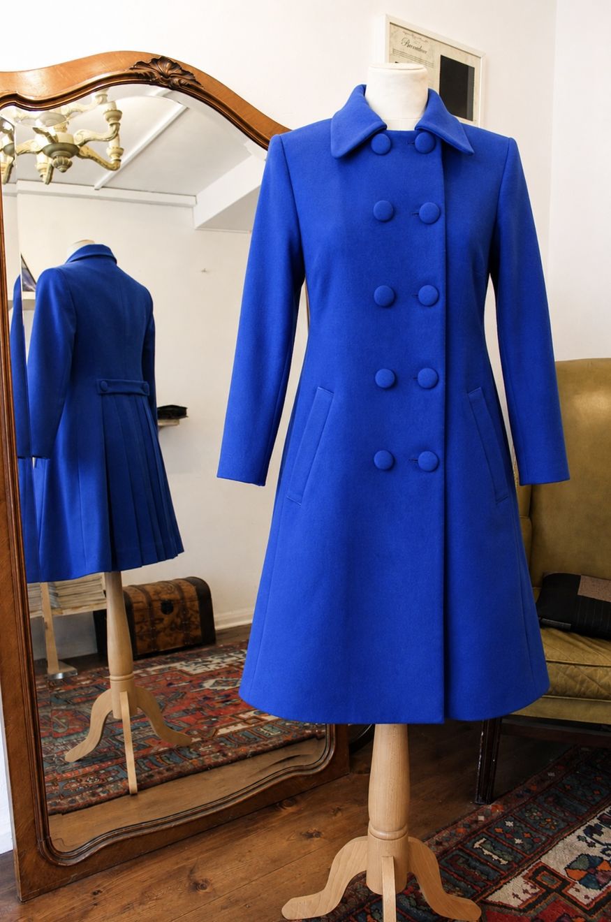 A royal blue double-breasted coat beside the studio mirror