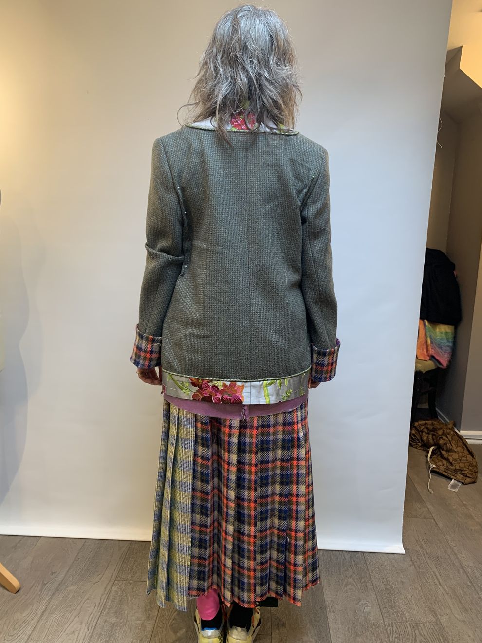 The back of a tweed jacket over a pleated tartan skirt