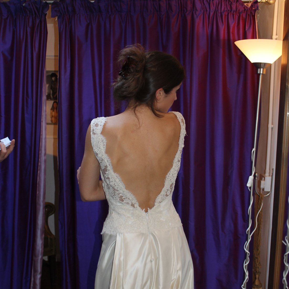 A client in a low-back lace gown being assessed in the fitting room
