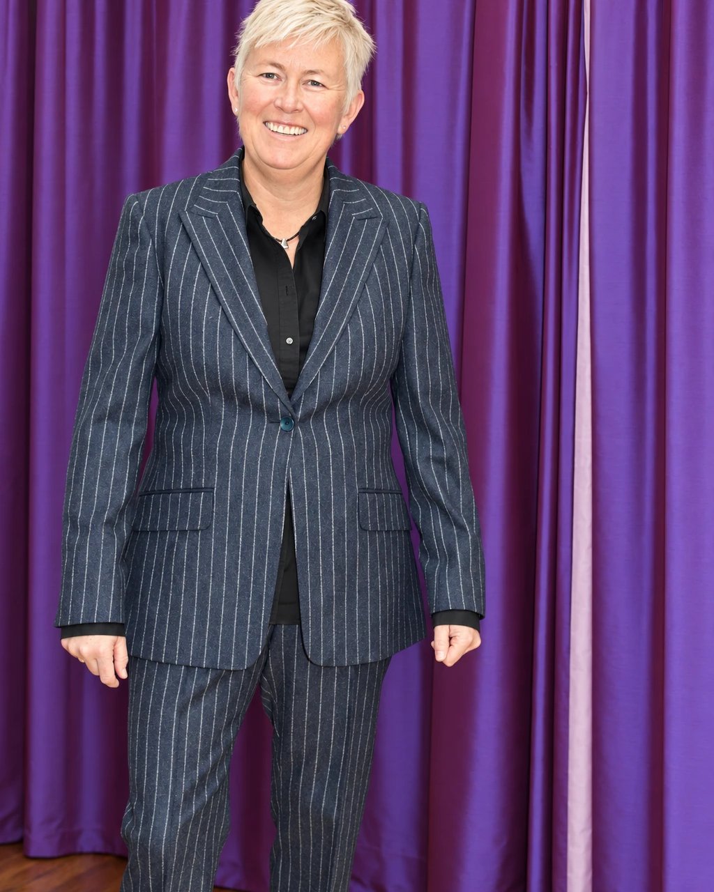 A client in her chalk-stripe flannel business suit, smiling in front of a purple curtain