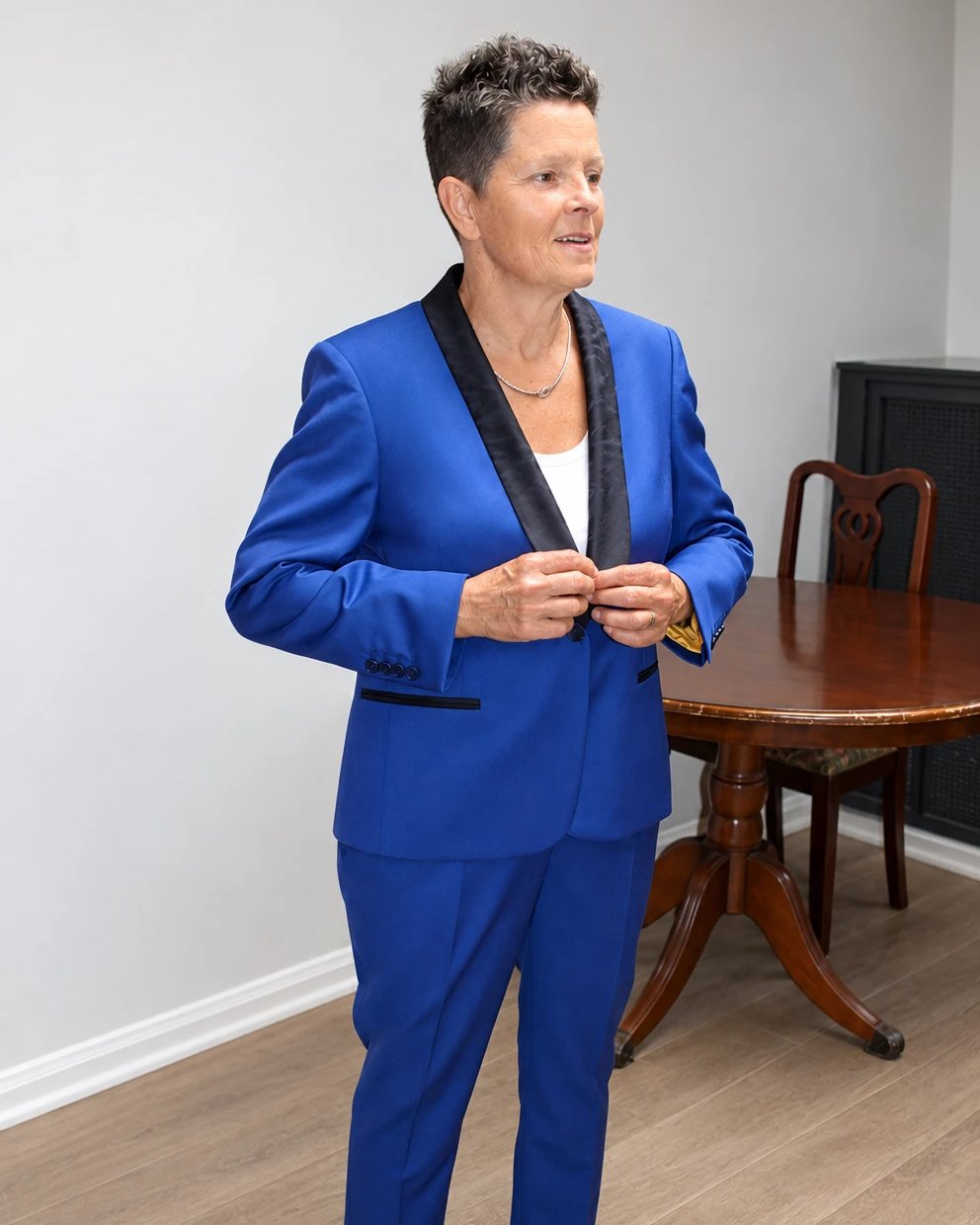 A client fastening her royal blue made-to-measure tuxedo suit with a black shawl lapel