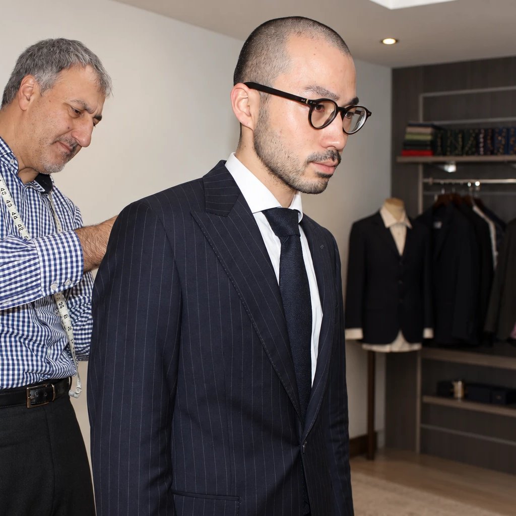 Orhan checking the shoulder of a client's pinstripe jacket in the fitting room