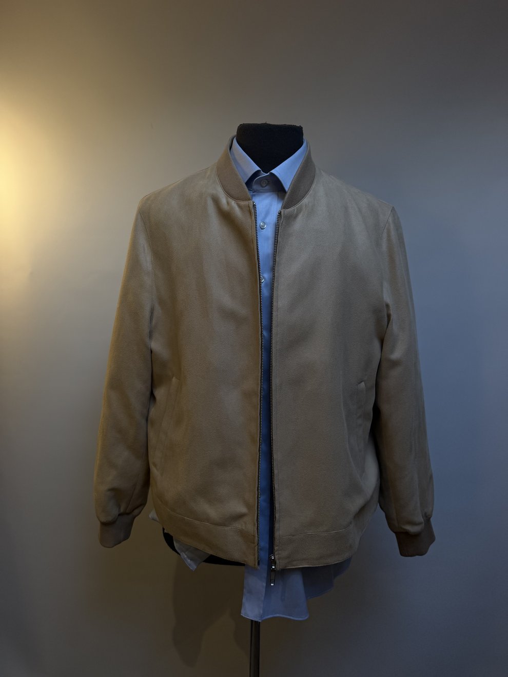 A beige harrington jacket worn open over a blue shirt