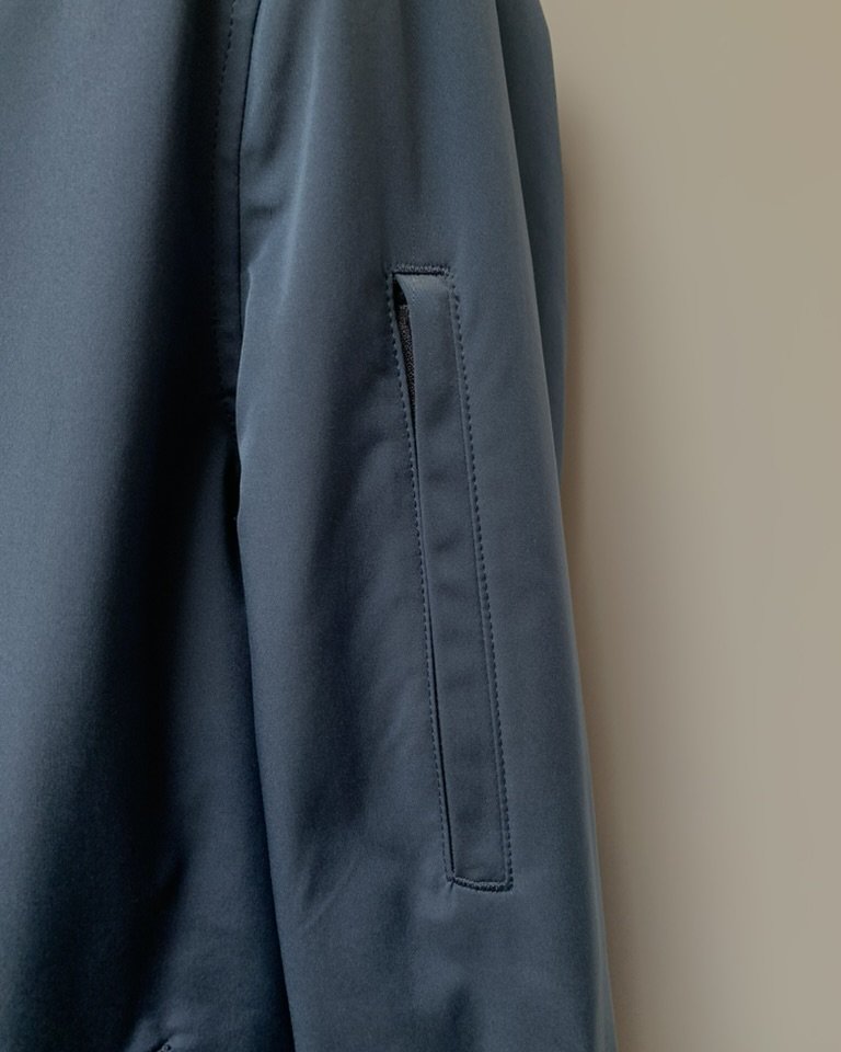 Welt pocket detail on a navy unstructured casual jacket
