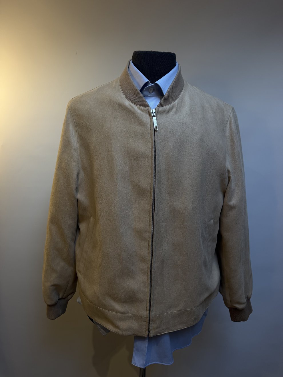 A taupe zip blouson zipped to the collar over a blue shirt