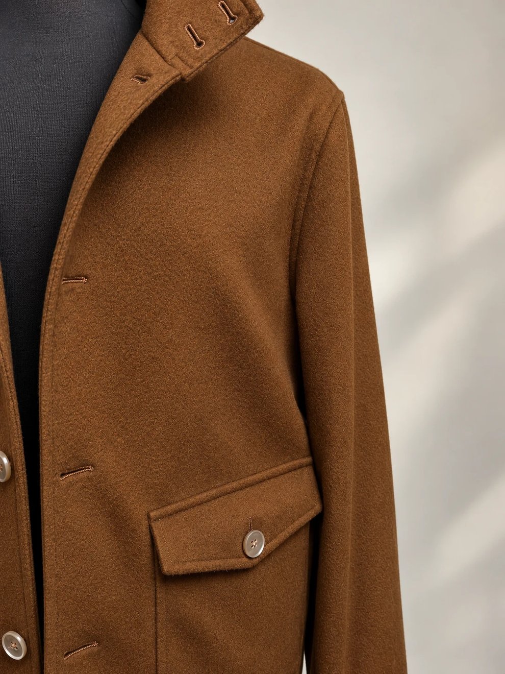 Flap-pocket and button detail on a tobacco brown wool jacket