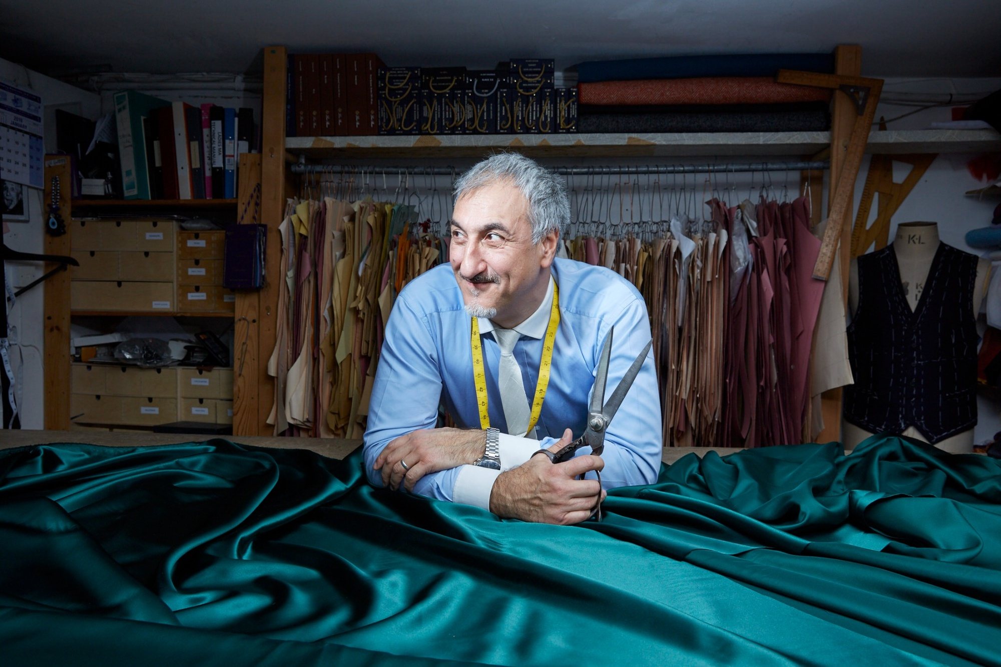 Orhan at the bench with his shears and a bolt of emerald satin