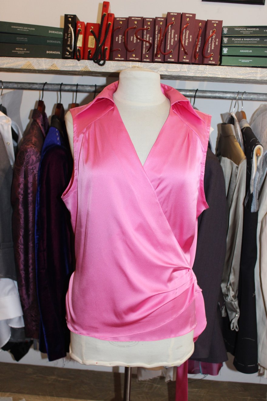 A pink satin sleeveless wrap blouse with a collar, on the studio mannequin