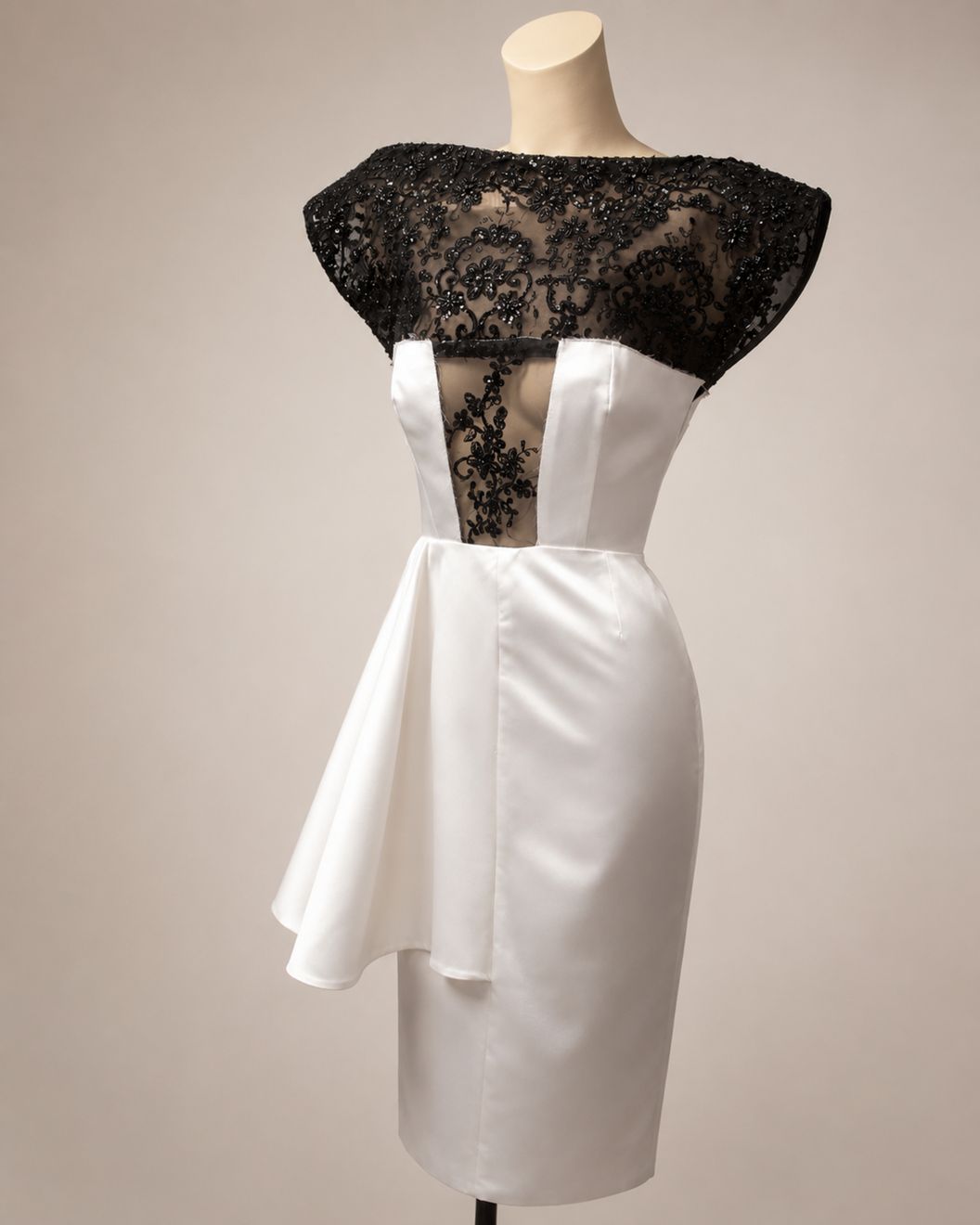 A couture dress of white satin and black beaded lace on a mannequin