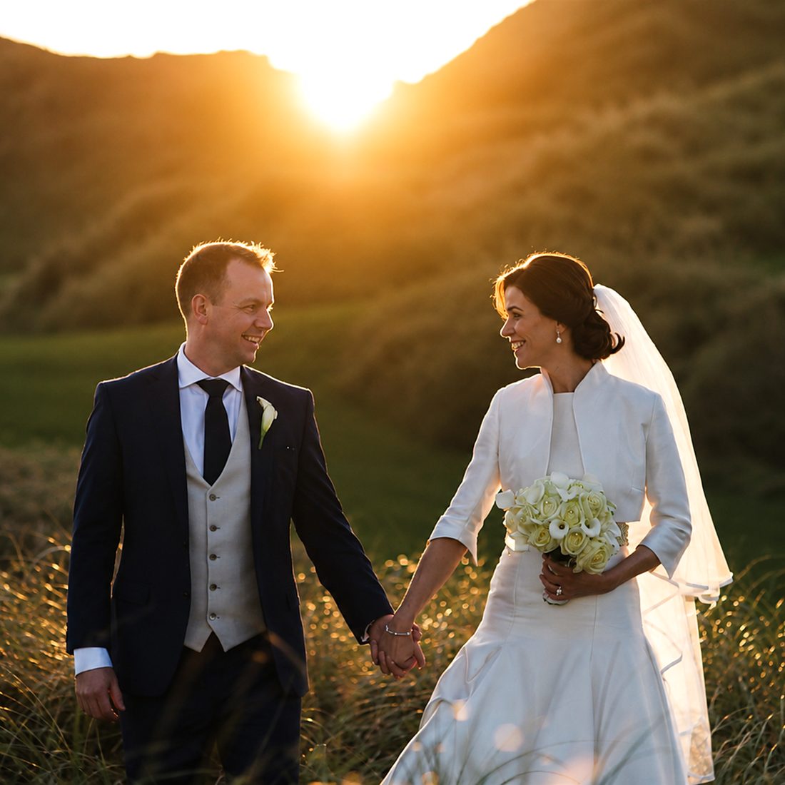 A couple walking through golden evening light on their wedding day