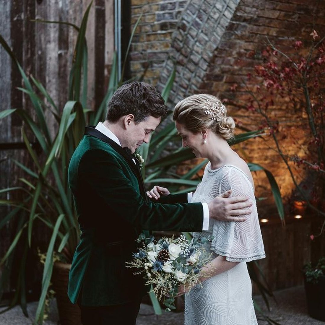 A bride in a beaded dress with her partner in a velvet dinner jacket